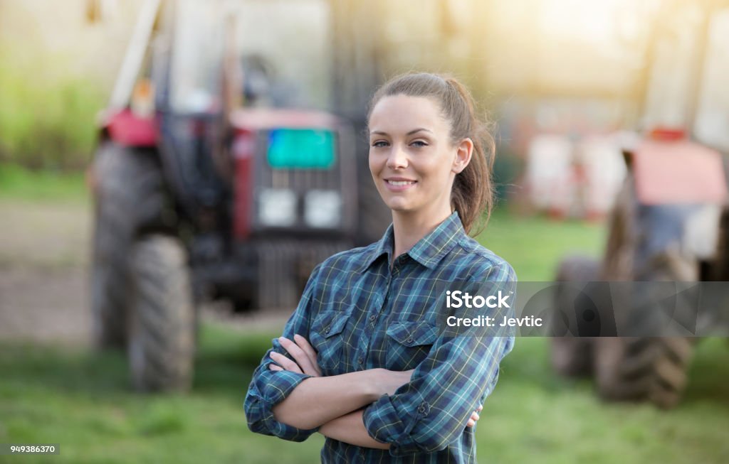 Agricoltore donna davanti ai trattori - Foto stock royalty-free di Agricoltore