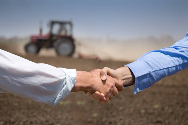 rolnicy potrząsają rękami przed ciągnikiem w polu - business agriculture equipment farm zdjęcia i obrazy z banku zdjęć