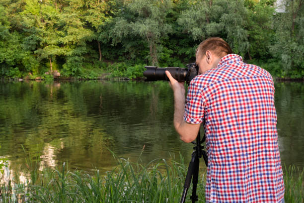 istock Photographer is shooting on the river bank, summer 949386452