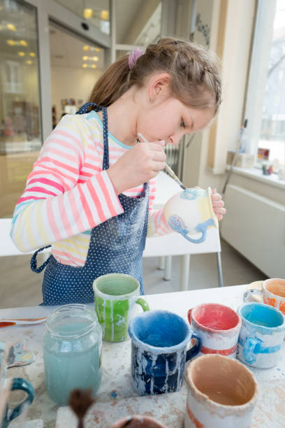 istock Skillful girl painting a clay cup at school 949388972