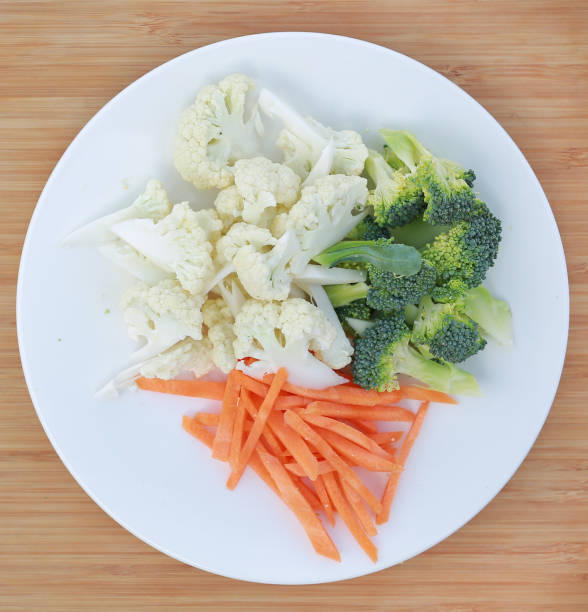 istock Cauliflower, broccoli and carrots on a plate against wooden background. 949394840