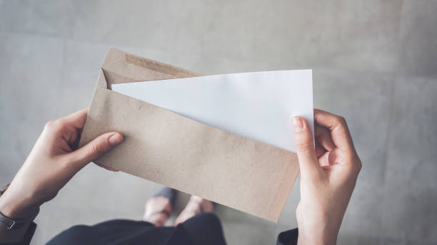Stand up woman holding white folded a4 paper and brown envelope Stand up woman holding white folded a4 paper and brown envelope envelope stock pictures, royalty-free photos & images