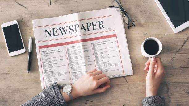 istock Woman reading newspaper and drinking coffee on table 949411966