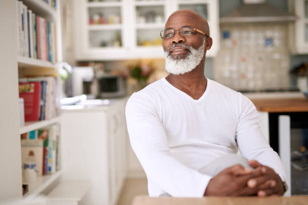 I'm just going to relax for the rest of the day Shot of a mature man looking thoughtful at home piece of mind stock pictures, royalty-free photos & images