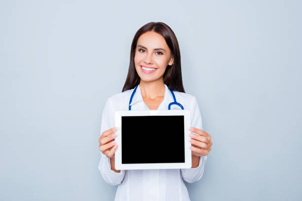 médecin assez souriant montrant l’écran noir de la tablette - doctor digital display digital tablet healthcare and medicine photos et images de collection