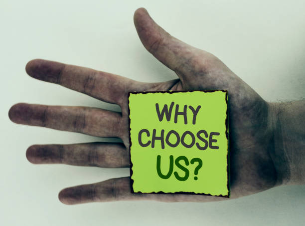 istock Writing note showing  Why Choose Us Question. Business photo showcasing Reasons to select our Services Products or Offers written on Sticky Note Paper placed on Dirty Hand on plain background. 949417836