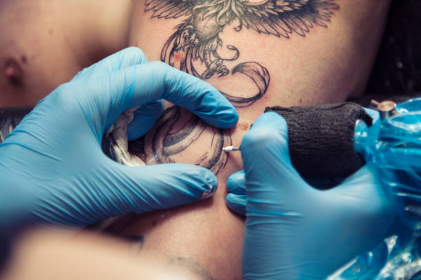 kobieta tatuażysta robi tatuaż na męskim ramieniu - tattoo men human arm shoulder zdjęcia i obrazy z banku zdjęć