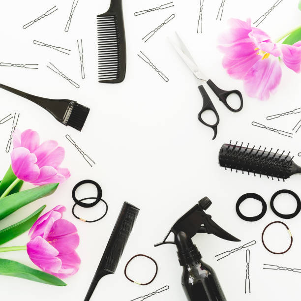 Frame with hairdresser tools - spray, scissors, combs, barrette and tulips on white background. Flat lay, top view