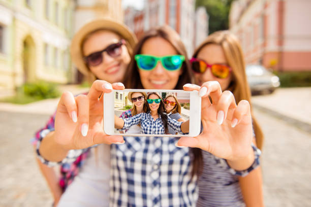 Three happy best girlfriends in glasses making selfie on smartphone Three happy best girlfriends in glasses making selfie on smartphone selfie photos stock pictures, royalty-free photos & images