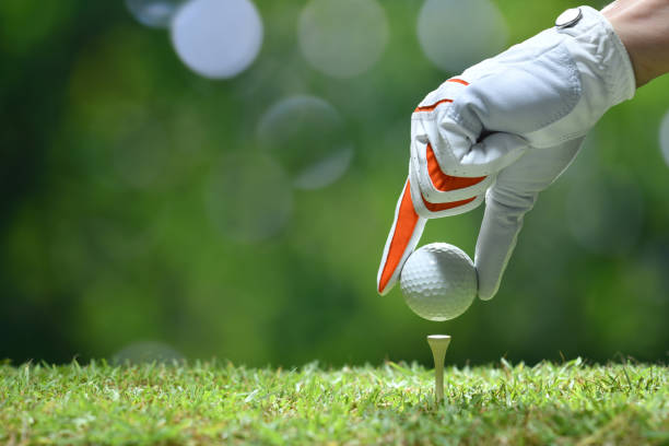 hand halten golfball mit abschlag am golfplatz - golf course fotos stock-fotos und bilder