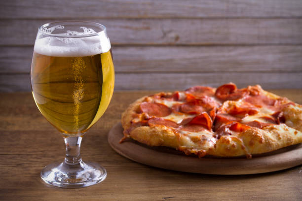 Beer and pizza on wooden table. Glass of beer. Ale and food concept Beer and pepperoni pizza on wooden table. Glass of beer. Ale and food concept. horizontal porter photos stock pictures, royalty-free photos & images