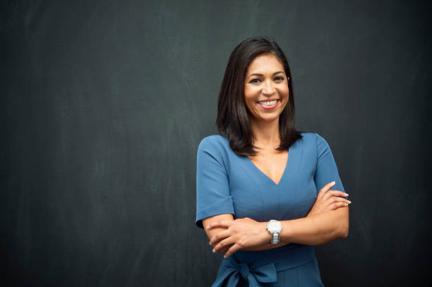 Strong Hispanic Woman Teacher Hispanic woman with chalk board background for copy space. long photos stock pictures, royalty-free photos & images
