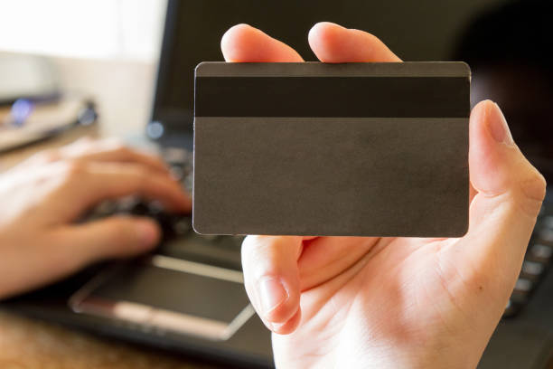 istock man hand holding blank credit card with laptop computer on background 949436516