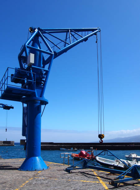 istock blue tower crane in a harbor dockyard with sea and boat dockside wall and blue sky 949441912