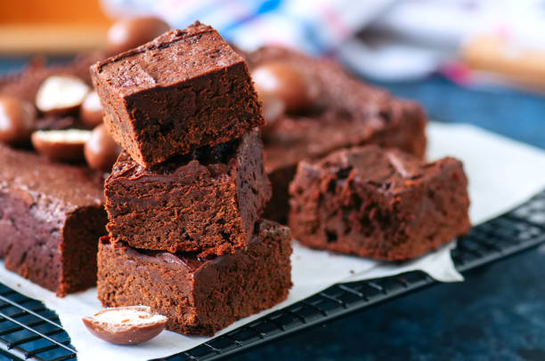 istock Dark chocolate brownie squares on a wire rack decorated with creamy chocolate eggs. Blue stone background. 949443830