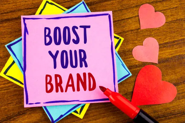 Photo of Conceptual hand writing showing Boost Your Brand. Business photo text improve your models name in your field overcome competitors written on Sticky note paper on wooden background Marker and Hearts