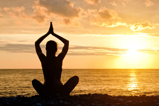 istock Woman with folded hands over head. Beach, sunset. Silhouette 949451062