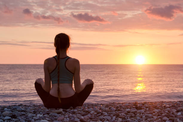 istock Woman meditating on the beach. Sunset 949451082