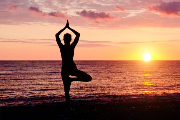 istock Woman at sunset practicing yoga. Seashore, silhouette 949451092