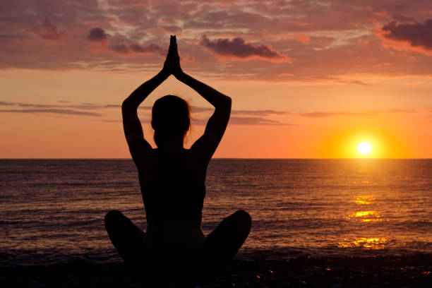 istock Woman with folded hands over head. Beach, sunset. Silhouette 949451094