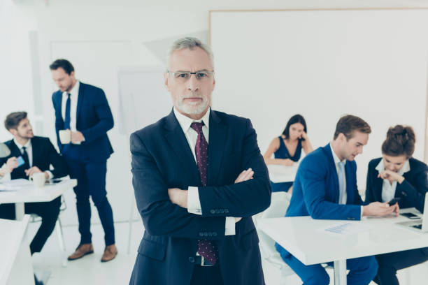 istock Senior partner of company with crossed hands while his staff working 949453542