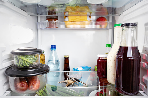 Photo of the inside of a refrigerator with a closed door with a bunch of keys between groceries.
