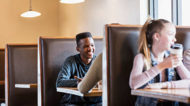 istock Teenagers sitting in restaurant booths, conversing 949470294