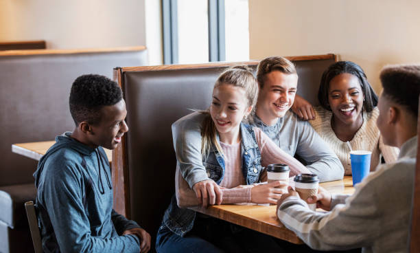istock Five teenagers sitting in restaurant booth, conversing 949470336