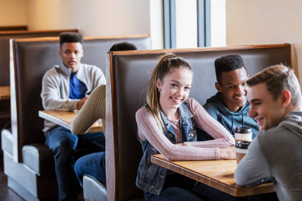 istock Teenagers sitting in restaurant booths, conversing 949470570