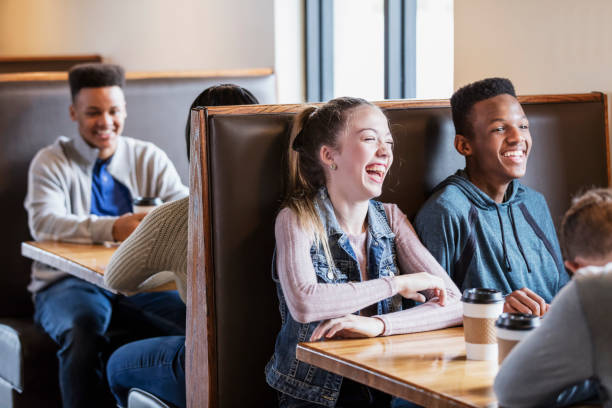 istock Teenagers sitting in restaurant booths, laughing 949470572