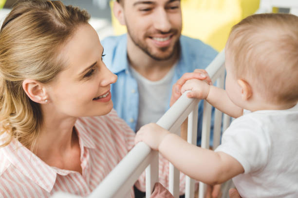 istock Young parents playing with infant daughter standing in crib 949472588