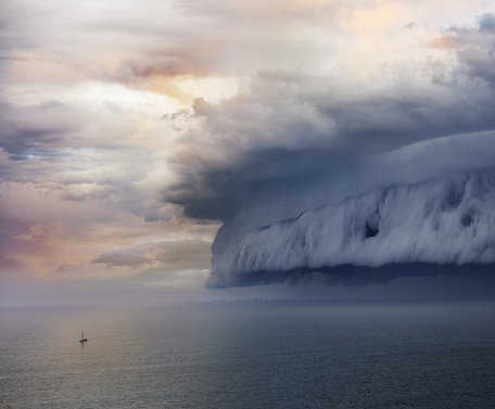 Tiny sailing boat and incoming storm