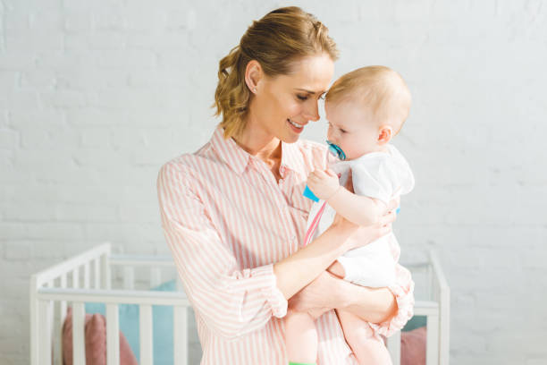 istock Young mother holding infant daughter with baby dummy 949476068