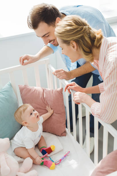 istock Smiling couple watching infant daughter in crib 949477010