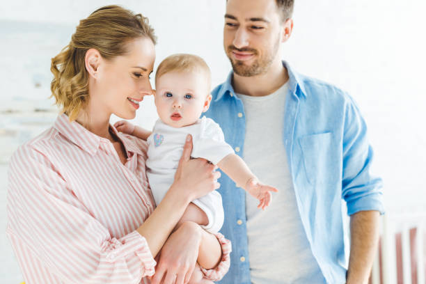 istock Mother holding infant daughter while father standing near 949480460