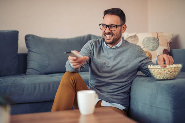 istock Young man watching TV on a sofa at home 949482222