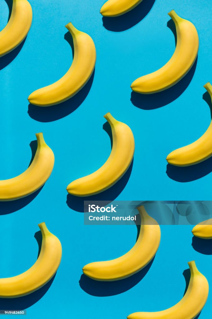 Background with bright bananas on blue Seamless backdrop of colorful yellow bananas composed on blue surface in glowing light. Repetition Stock Photo
