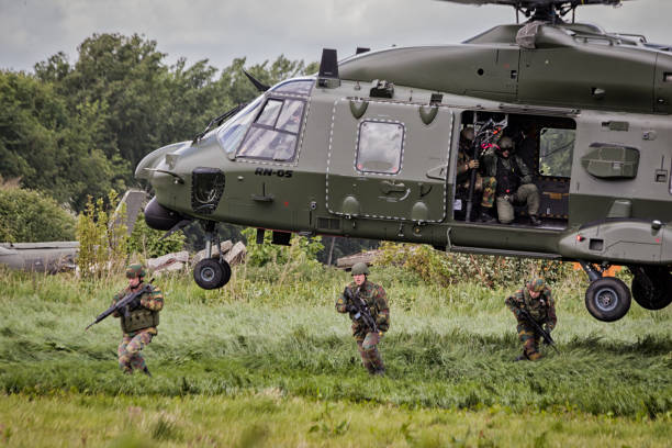 Soldiers disembark helicopter BEAUVECHAIN, BELGIUM - MAY 20, 2015: Soldiers disembark from an army NH90 helicopter. nato stock pictures, royalty-free photos & images
