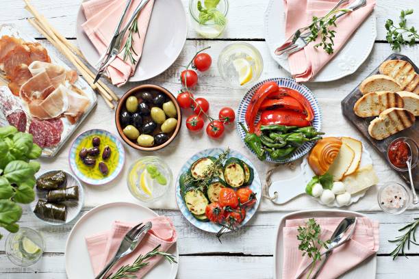 istock Mediterranean appetizers table concept. Diner table with antipasto selection: grilled vegetables, cured meat and salami,  jamon, olives, cheese, hummus and roasted bread. 949486176
