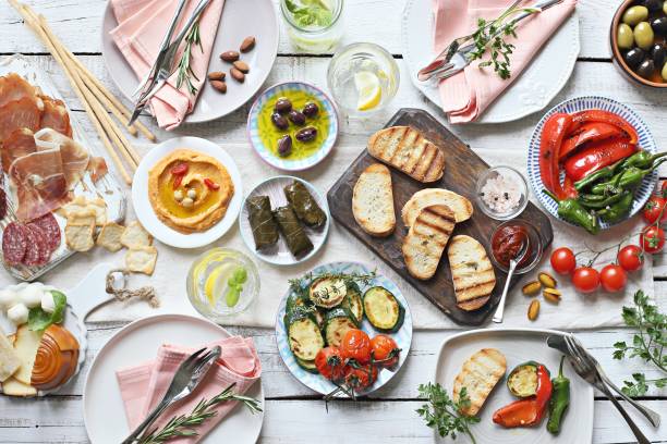 istock Mediterranean appetizers table concept. Diner table with antipasto selection: grilled vegetables, cured meat and salami,  jamon, olives, cheese, hummus and roasted bread. 949486252