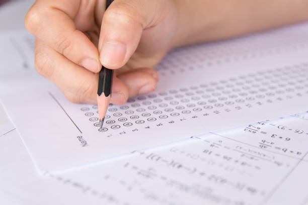 istock Students hand holding pencil writing selected choice on answer sheets and Mathematics question sheets. students testing doing examination. school exam 949490046