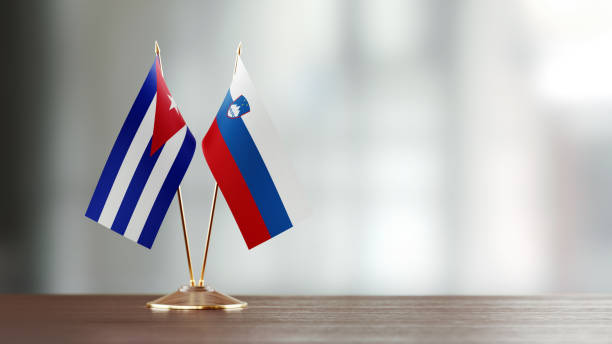 istock Cuban And Slovenian Flag Pair On A Desk Over Defocused Background 949496534
