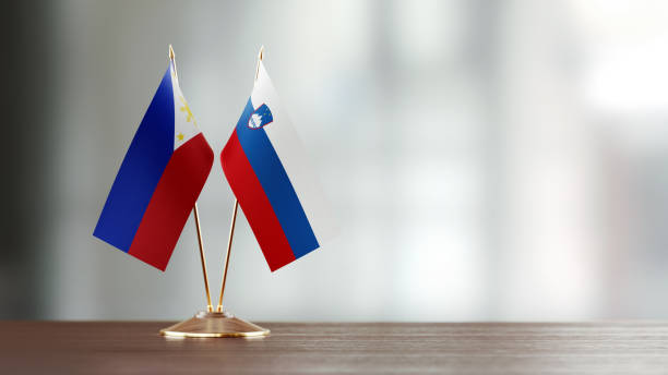 istock Philippines And Slovenian Flag Pair On A Desk Over Defocused Background 949499162
