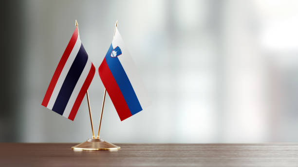 istock Thai And Slovenian Flag Pair On A Desk Over Defocused Background 949499266