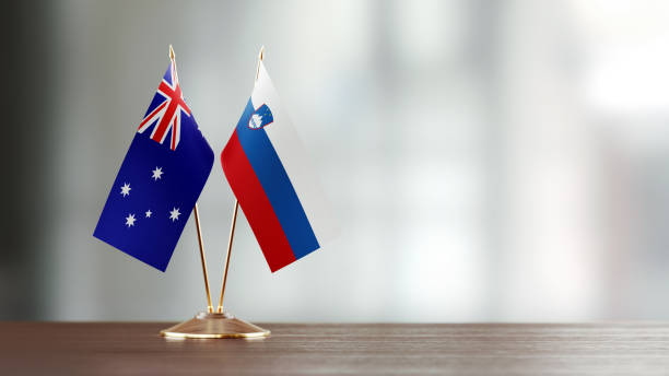 istock Australian And Slovenian Flag Pair On A Desk Over Defocused Background 949500190