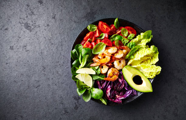 Colorful Poke Bowl with Roasted Sesame Prawns, Red Cabbage, Avocado, Cherry Tomatoes, Corn Salad and Lettuce Colorful Poke Bowl with Roasted Sesame Prawns, Red Cabbage, Avocado, Cherry Tomatoes, Corn Salad and Lettuce salad bowl photos stock pictures, royalty-free photos & images