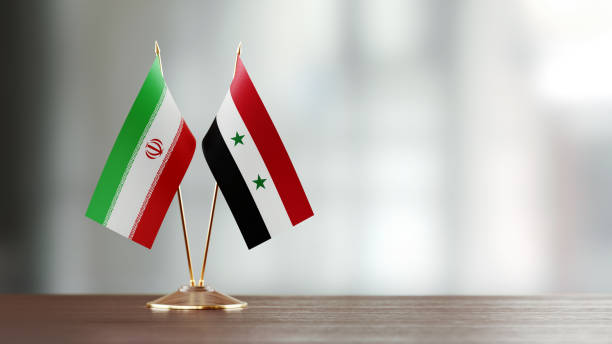 istock Iranian And Syrian Flag Pair On A Desk Over Defocused Background 949503712