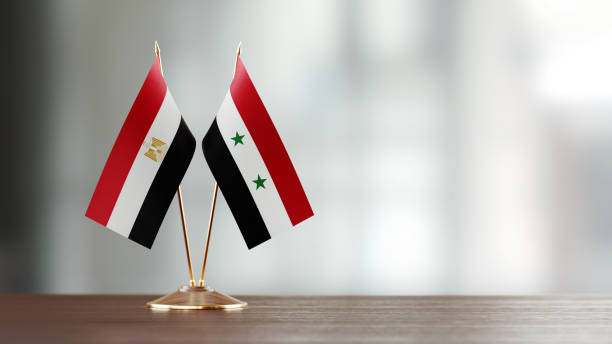 istock Egyptian And Syrian Flag Pair On A Desk Over Defocused Background 949503984