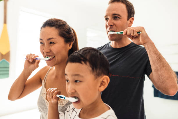 family brushing teeth together in the bathroom - human teeth child smiling family imagens e fotografias de stock