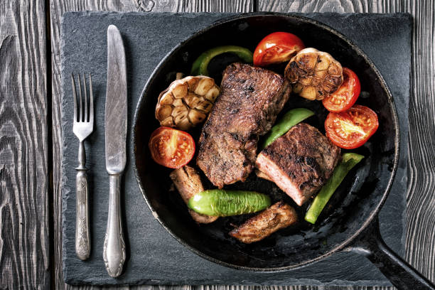 istock Frying pan with steak and baked vegetables on the table 949514210